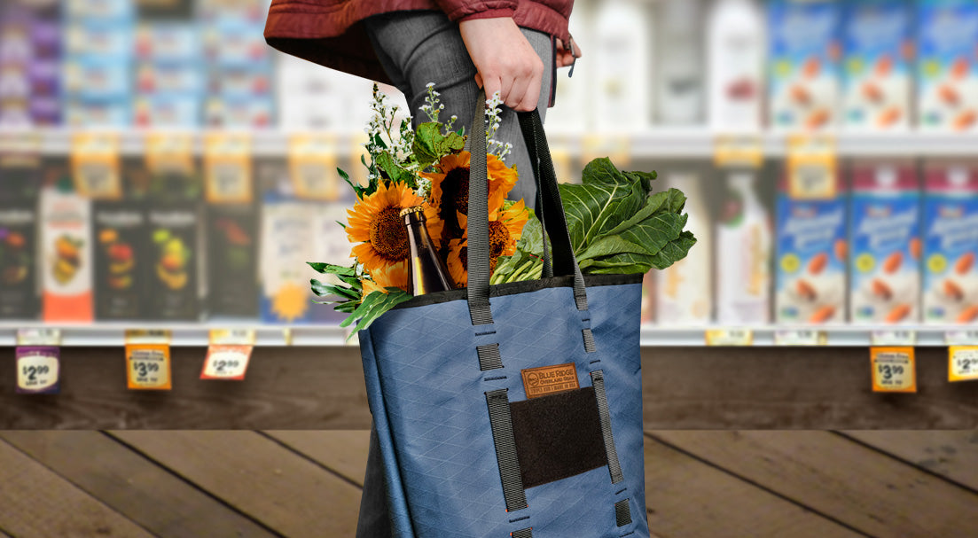 X-Pac Market Tote bag by Blue Ridge Overland Gear - young woman holds high end tote full of groceries and flowers in health food store.