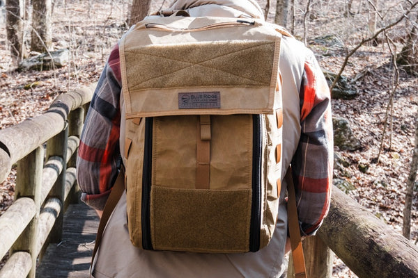 Person wearing a coyote brown backpack in a forest setting