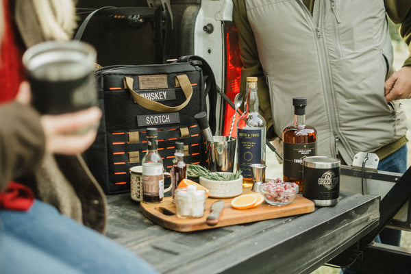 Speakeasy Bourbon Bag by Blue Ridge Overland Gear set up as a portable cocktail bar with whiskey, rum, bar tools, and drink accessories.
