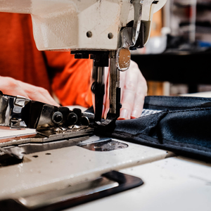 Person operating a sewing machine with fabric in a workshop setting