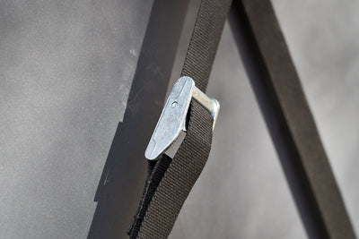 This Overland Fridge Tie-Down Strap features a heavy-duty metal cam buckle for tightening.